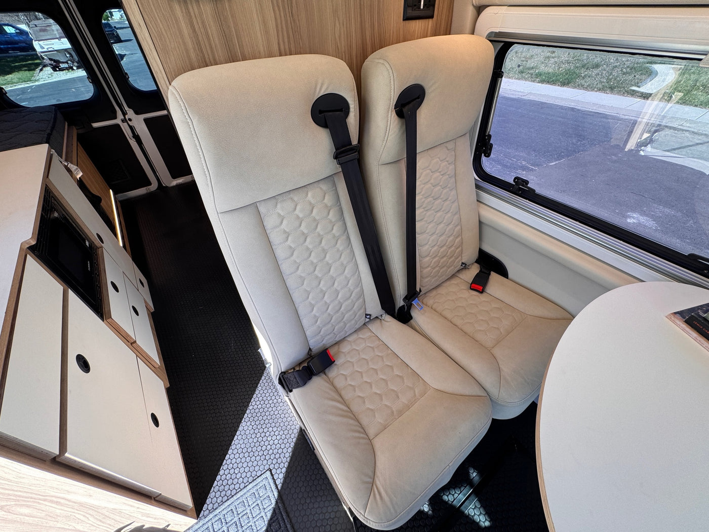 rv rental: Modern camper van interior with two comfortable rear seats, dining table, and sleek cabinetry. — photo 12