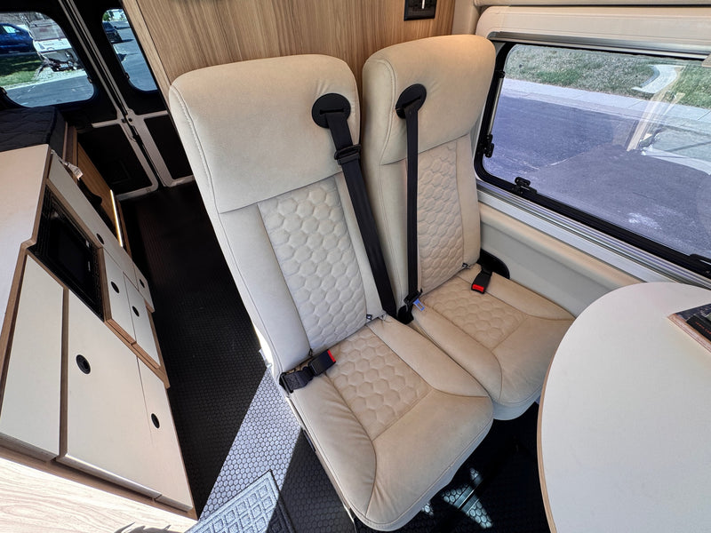 rv rental: Modern camper van interior with two comfortable rear seats, dining table, and sleek cabinetry. — photo 12