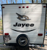 Back of a white Jayco travel trailer, often an RV rental, showing its spare tire, taillights, and travel stickers at a campsite.