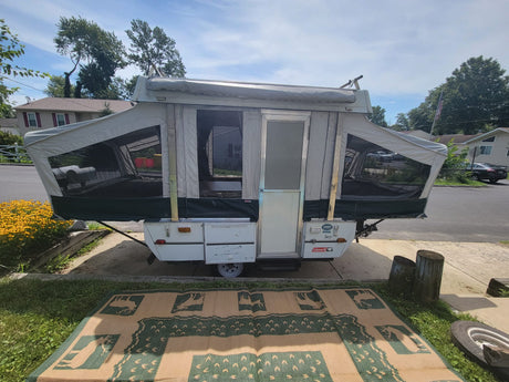 This pop-up tent trailer, often an RV rental, is fully set up, showcasing its roomy interior and outdoor mat.