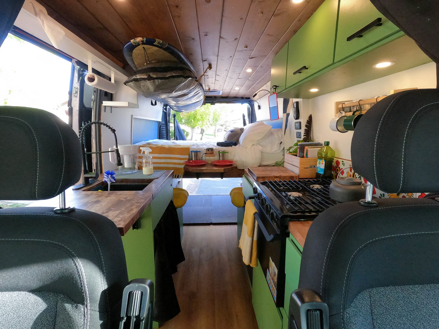Inside a modern rv rental camper van, featuring a full kitchen, comfortable bed, and overhead storage for adventure gear. — photo 6