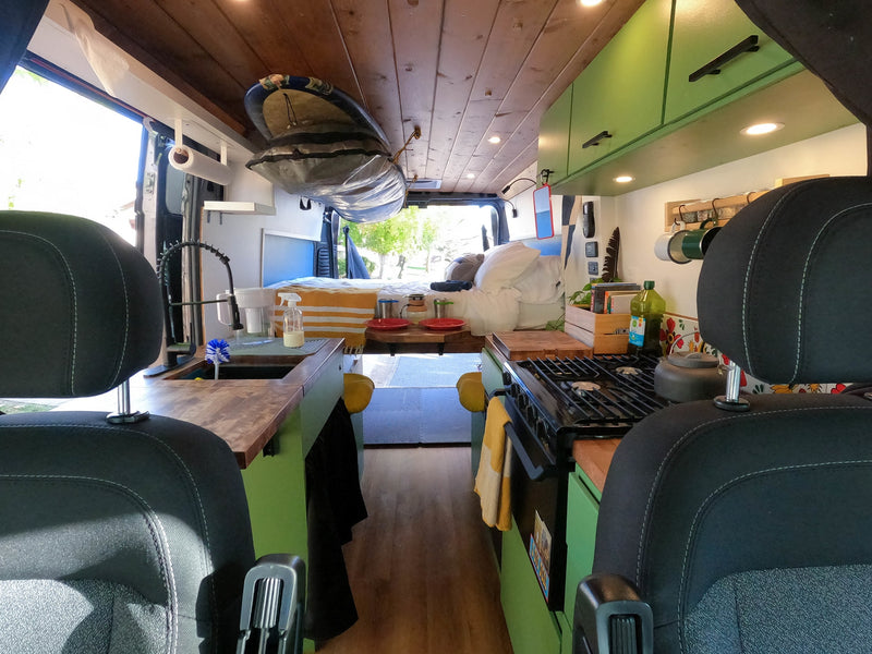Inside a modern rv rental camper van, featuring a full kitchen, comfortable bed, and overhead storage for adventure gear. — photo 6