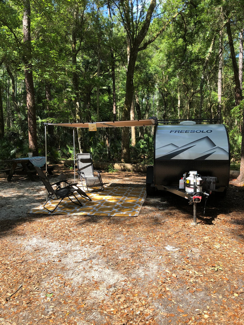 Experience tranquil nature with this Freesolo RV rental setup, featuring an awning, chairs, and picnic table at a shady forest campsite. — photo 14