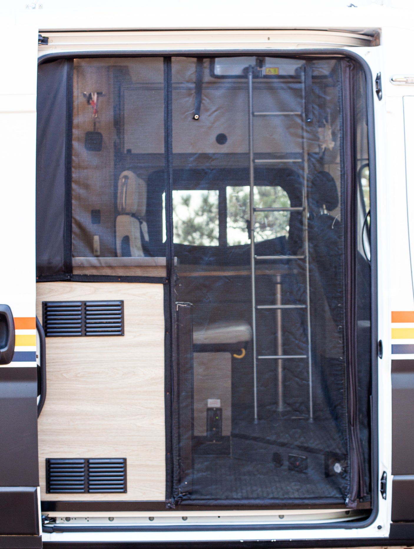 RV rental: Open side door and mesh screen offer a peek into the cozy van interior with a ladder and vents.