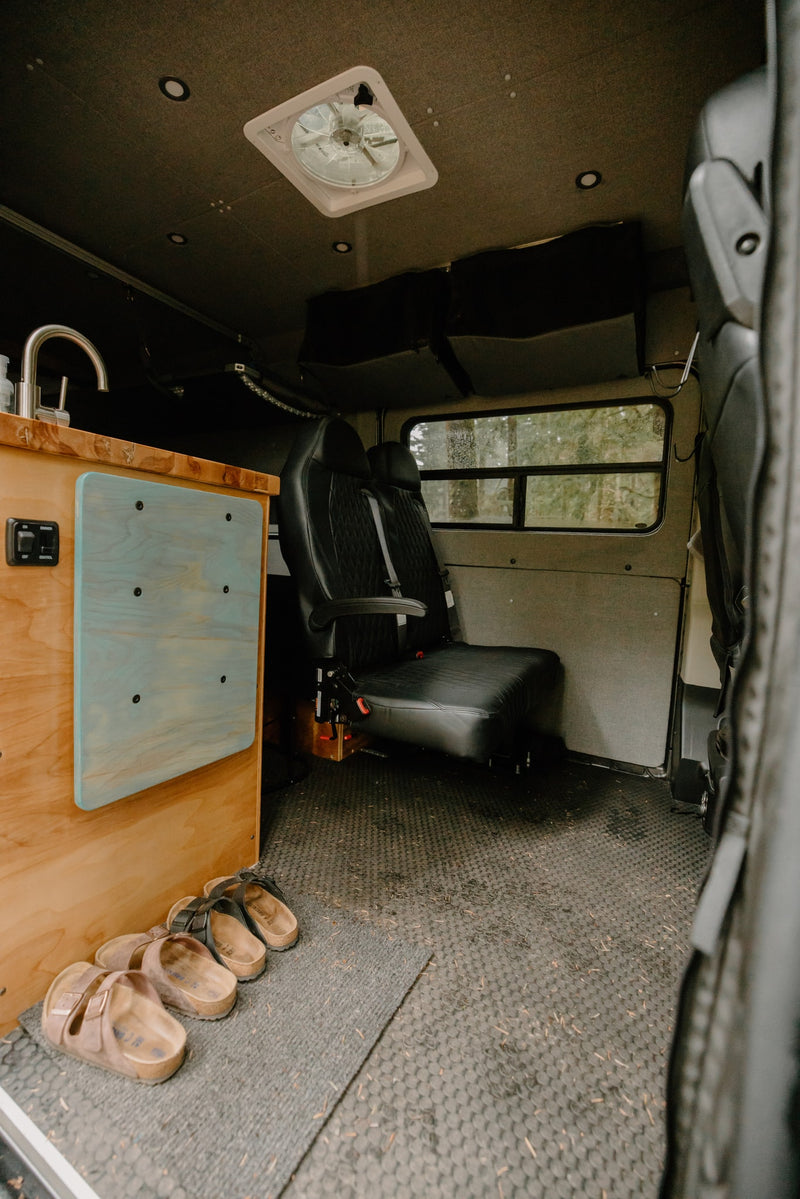 Cozy RV rental interior: sink, passenger seat, and forest views. — photo 5