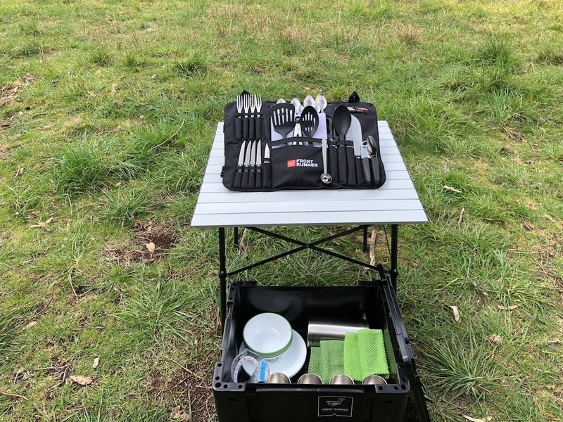 RV rental cooking gear setup: Front Runner utensils on a table, plates/cups in a box, ready for outdoor meals. — photo 13