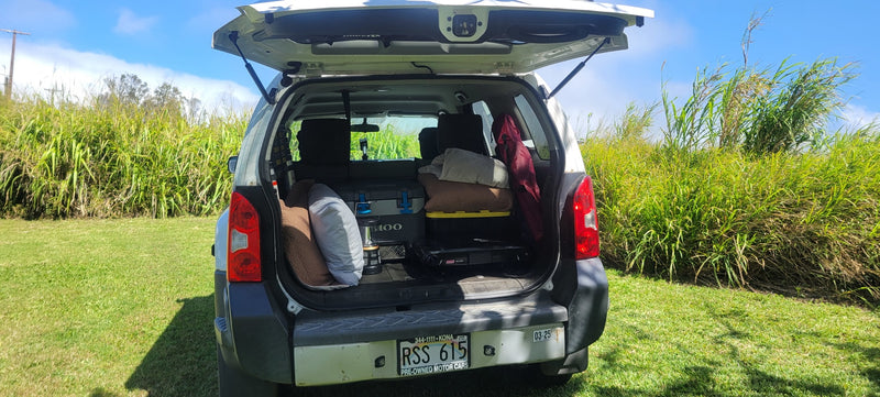 White SUV tailgate open, packed with camping gear (cooler, pillows, stove). Great for an RV rental style outdoor getaway. — photo 6