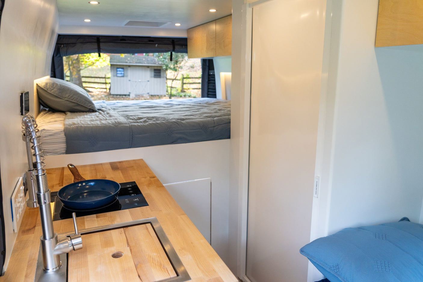This RV rental's van conversion offers a compact kitchen and comfy elevated bed, ideal for tiny home on wheels travel.