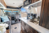 Explore this well-equipped RV rental interior with a compact kitchen, lounge, and scenic view out front.