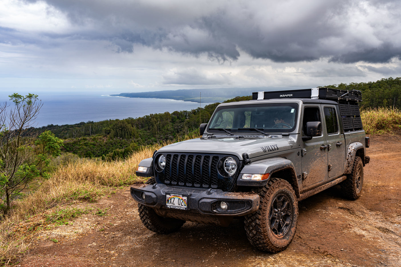 Experience Hawaii's coast with this muddy Jeep Gladiator, featuring an iKamper rooftop tent. Ideal for an rv rental adventure.