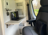 RV rental mobile office: MacBook on a fold-down desk with a cell booster, comfortable seat, and nature views outside.