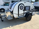 A white Boondock teardrop RV/camper, ideal for RV rental adventures, featuring off-road tires and a front storage box.