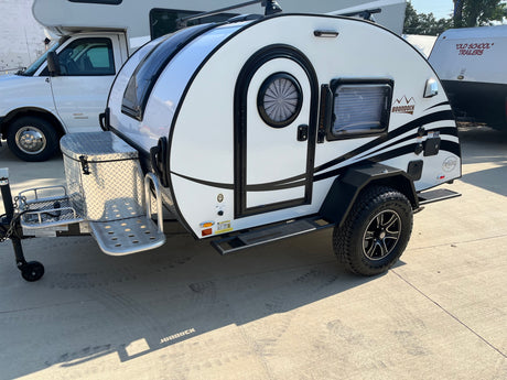 A white Boondock teardrop RV/camper, ideal for RV rental adventures, featuring off-road tires and a front storage box.