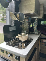 An RV rental's cozy kitchenette, featuring a pot on the stove, sink, and a unique topographic counter pattern.