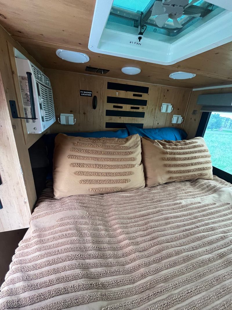 Comfortable RV rental bed with decorative pillows, AC unit, and overhead fan for a cozy night's sleep. — photo 7