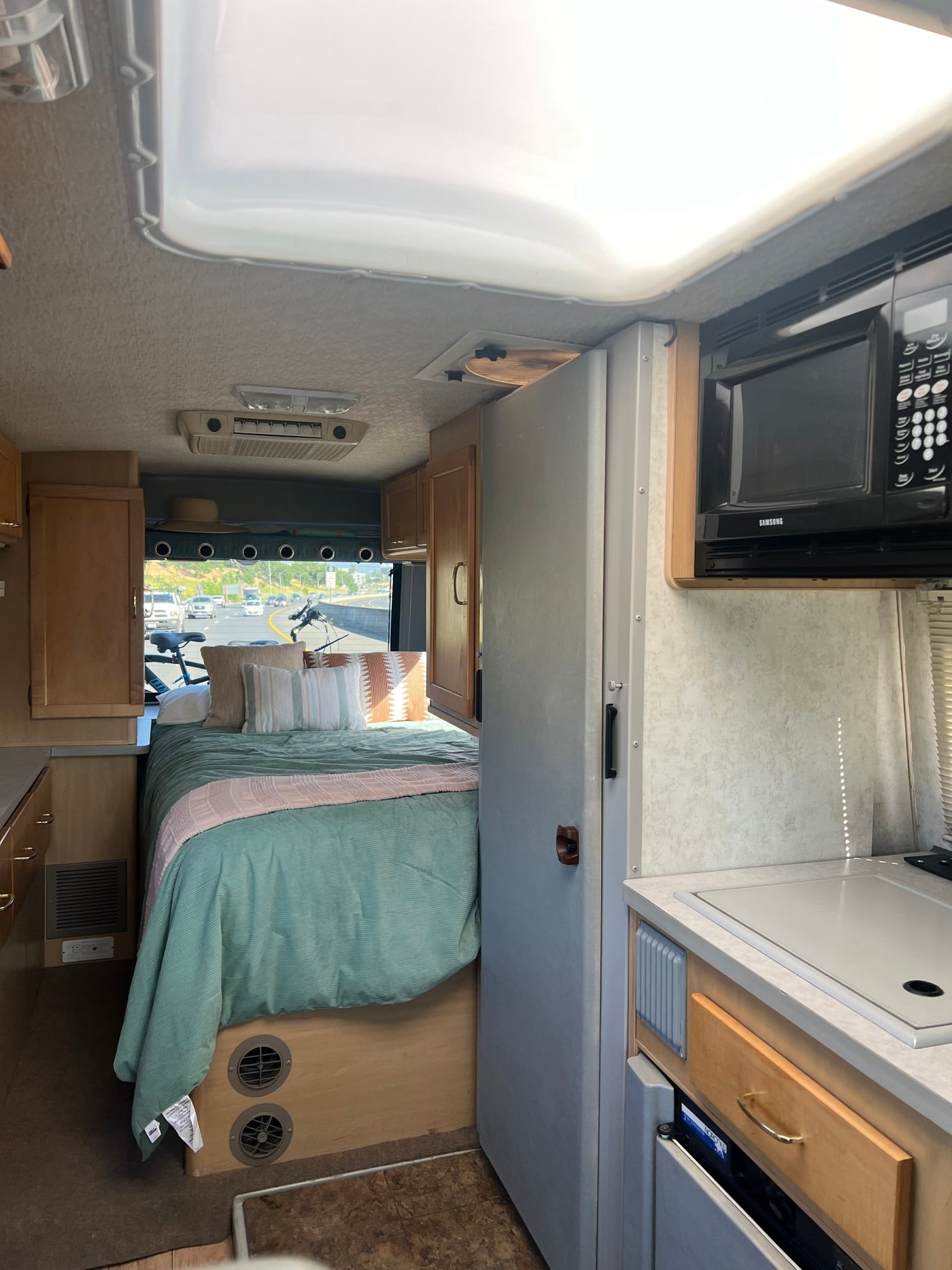  perfect for your next rv rental.|Cozy RV rental interior featuring a teal-covered bed and compact kitchen space — photo 5