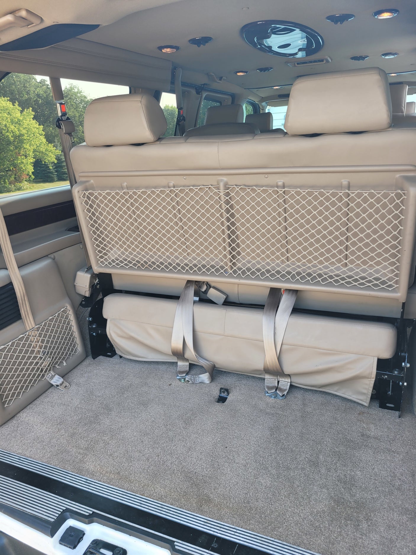 Spacious RV rental van interior with comfortable seating/bed, overhead lights, and handy mesh storage.