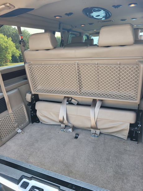 Spacious RV rental van interior with comfortable seating/bed, overhead lights, and handy mesh storage.