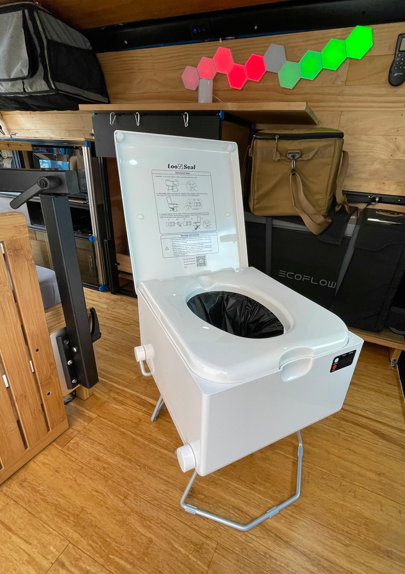 Portable Loo Seal toilet in an RV rental, with an Ecoflow unit, hexagonal lights, and wooden floor.