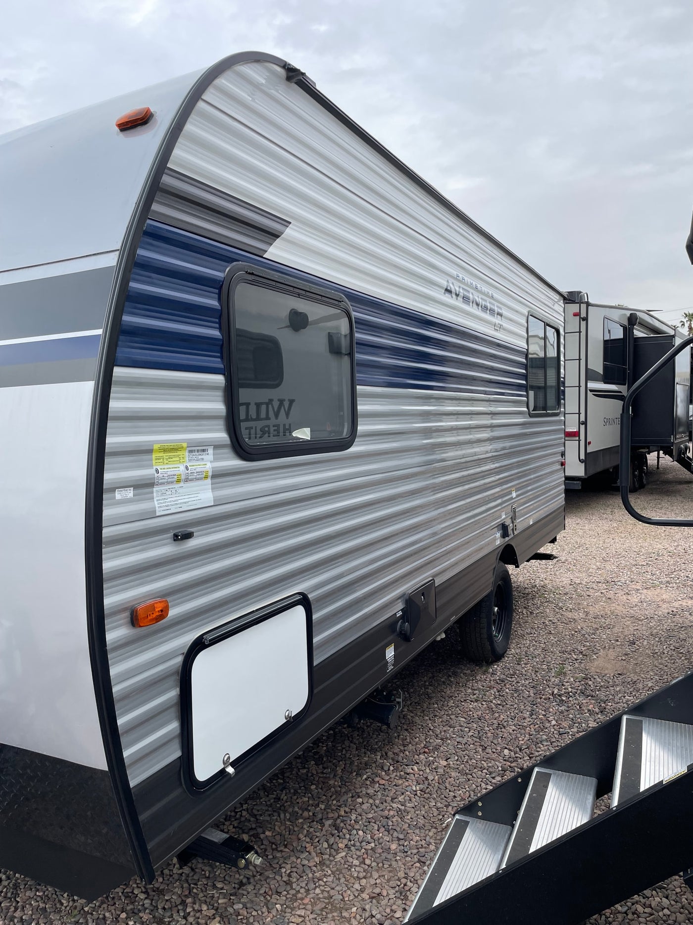 Spacious grey and blue travel trailer RV, perfect for your next RV rental adventure, parked on a gravel lot. — photo 8