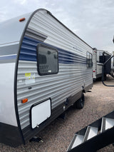Spacious grey and blue travel trailer RV, perfect for your next RV rental adventure, parked on a gravel lot.