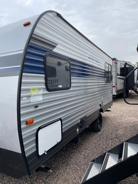 Spacious grey and blue travel trailer RV, perfect for your next RV rental adventure, parked on a gravel lot.