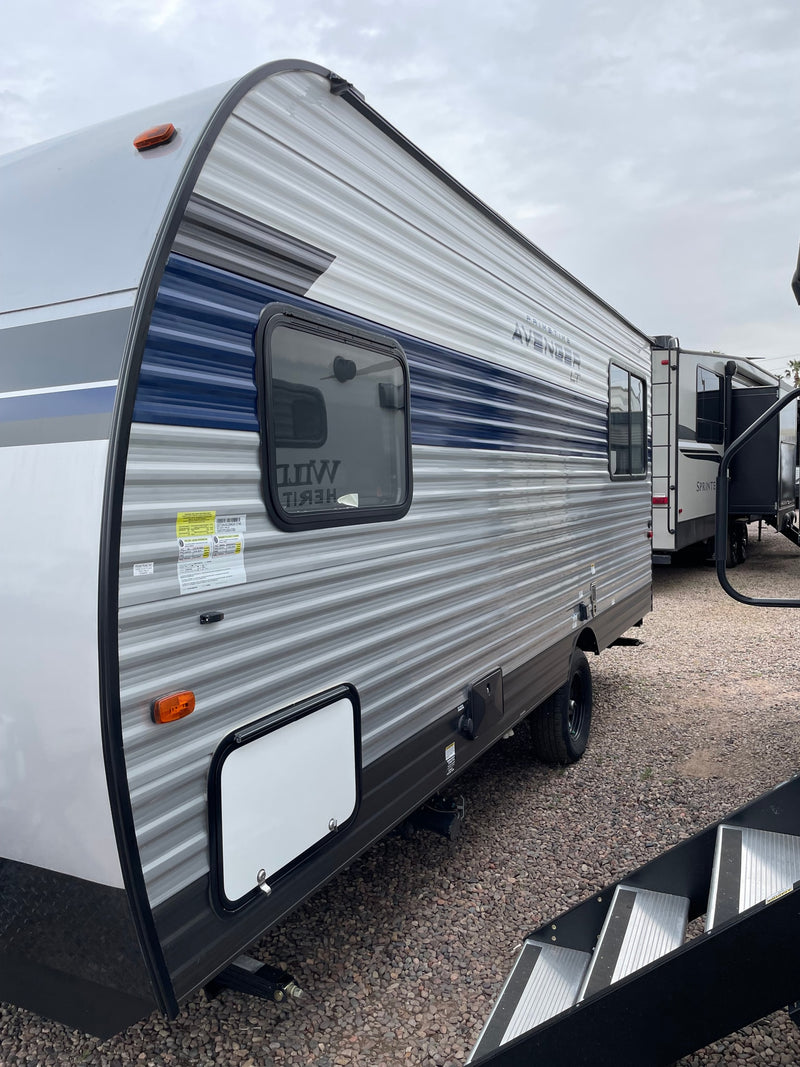 Spacious grey and blue travel trailer RV, perfect for your next RV rental adventure, parked on a gravel lot. — photo 8