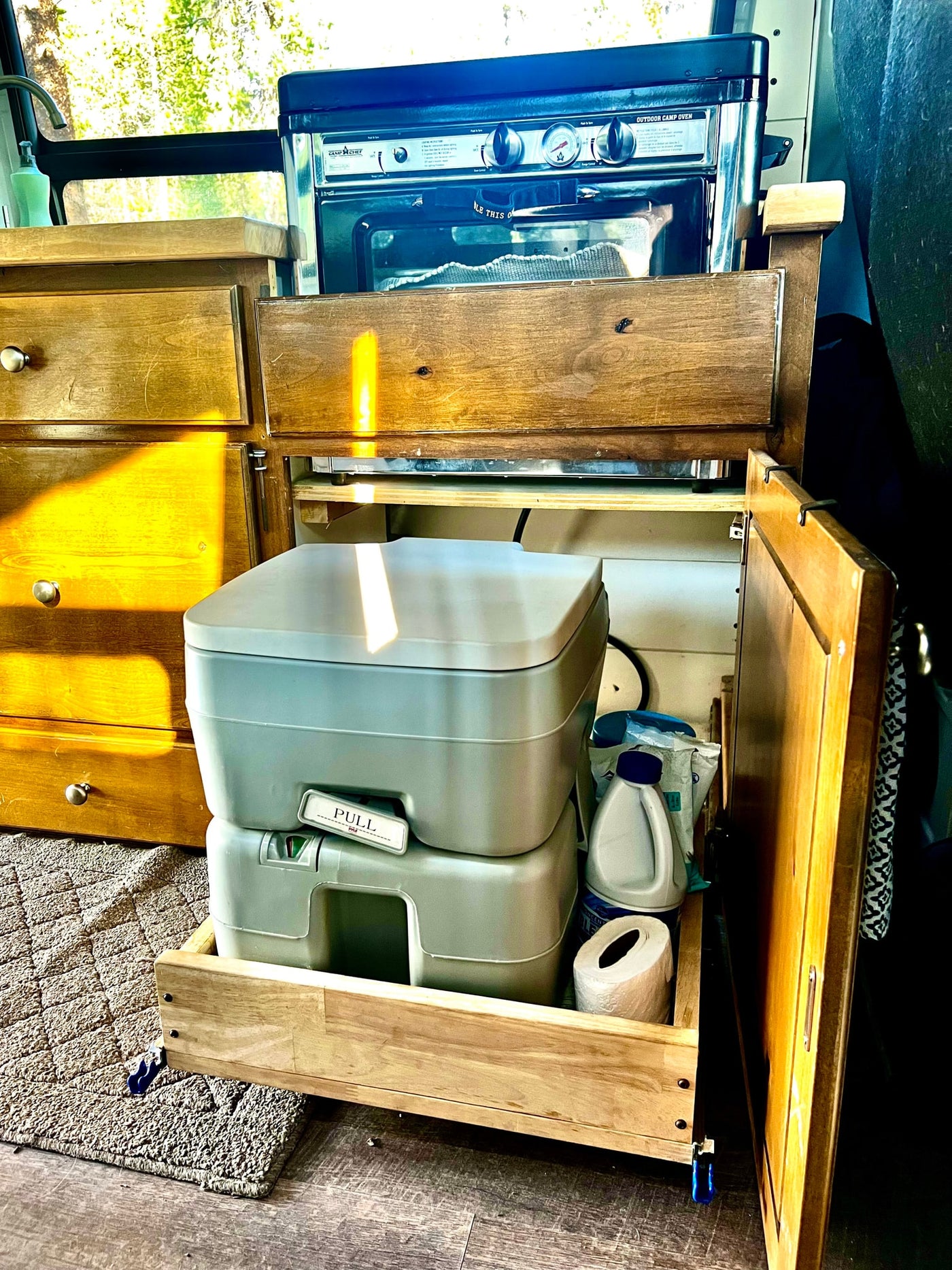 RV rental features: A portable camping toilet and a Camp Chef oven nestled in a compact camper van. — photo 16