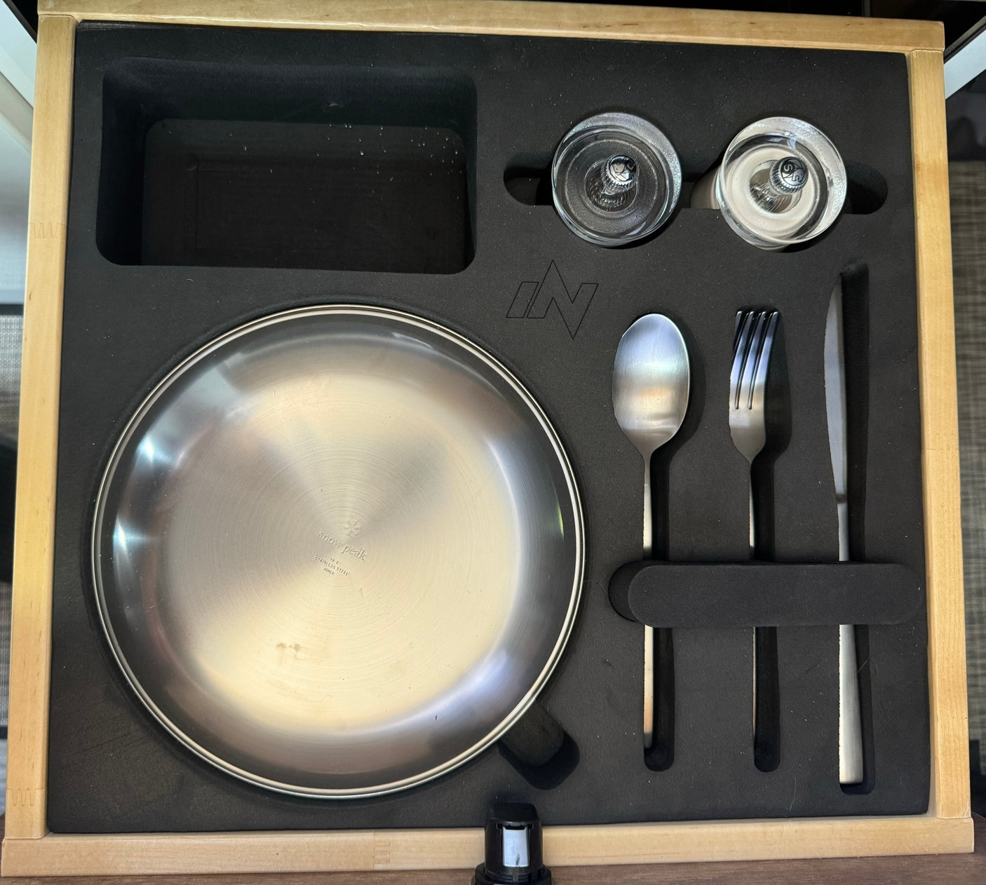 Compact and organized kitchen set with Snow Peak plate, cutlery, and shakers, ideal for your RV rental adventures.