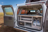 This RV rental shows a camper van's rear: integrated kitchen with pull-out stove, fridge, sink, and water tanks for mobile adventures.