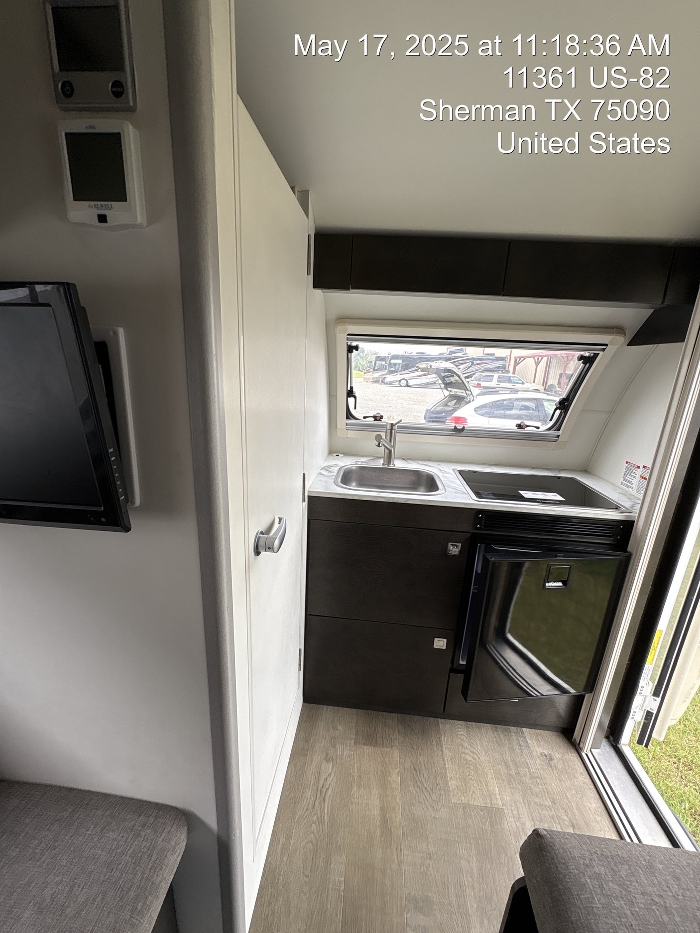 Experience this cozy RV rental interior, featuring a compact kitchen with sink & cooktop, a small fridge, and a living area with TV.