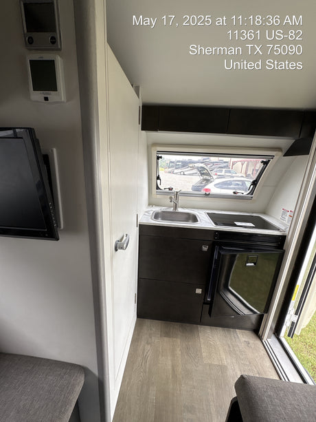 Experience this cozy RV rental interior, featuring a compact kitchen with sink & cooktop, a small fridge, and a living area with TV.
