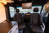 Inside a modern rv rental van, showing the front seats, dashboard, ceiling screen, and a custom interior counter.