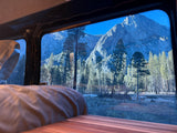 Gaze at majestic mountains and a serene forest from the window of your comfortable *rv rental*, offering a cozy nature escape.