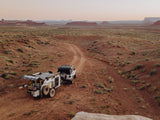 Explore the desert! This white Jeep pulls an off-road RV rental, its rear kitchen open for remote adventure camping.