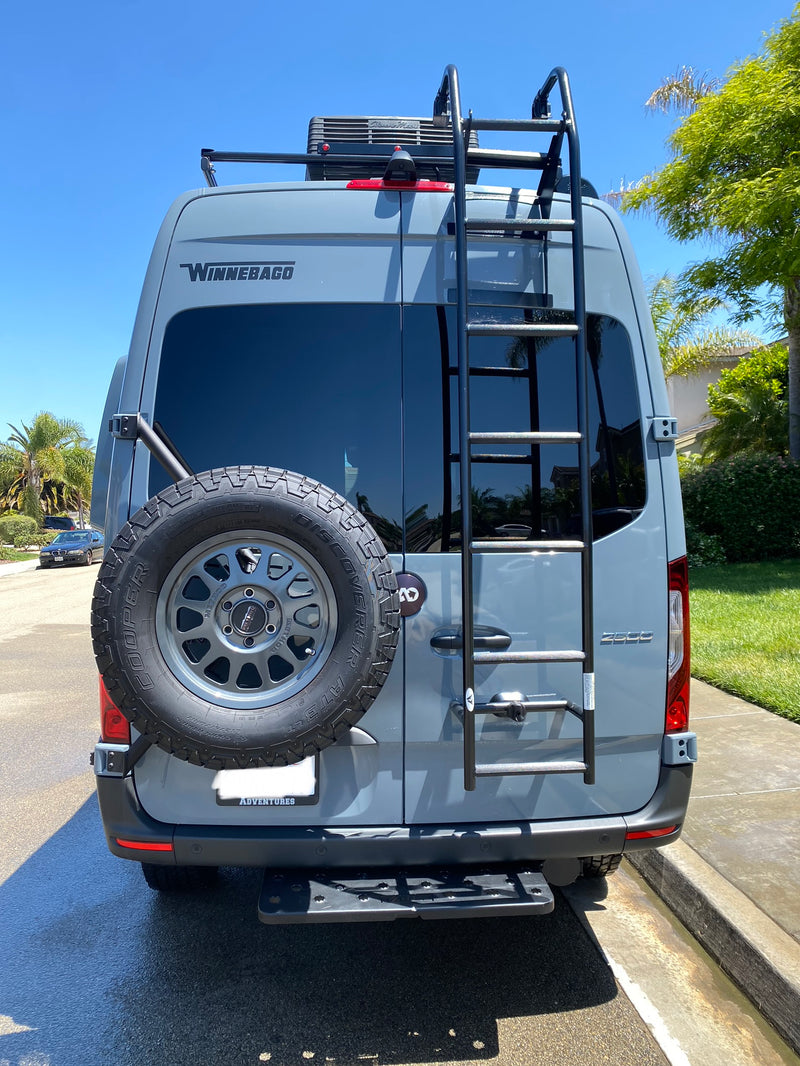 Rear view of a gray Winnebago camper van (rv rental) with spare tire, roof unit, and ladder, ready for adventures. — photo 3