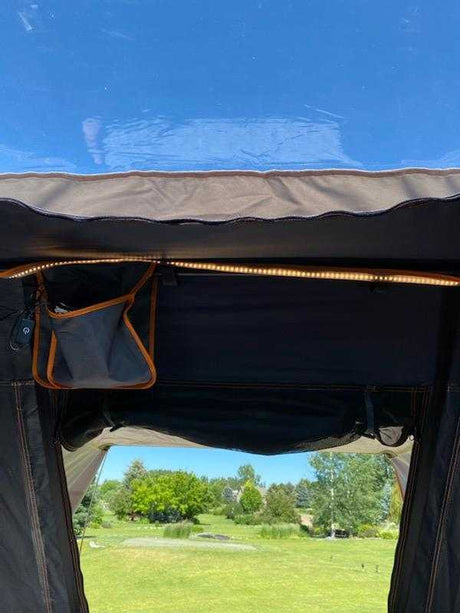 Inside an rv rental, LED lights illuminate a storage pouch with a view of a green landscape and trees.
