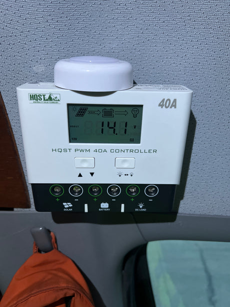 HQST 40A solar charge controller showing 14.1V, managing solar power to batteries and DC loads in this RV rental setup.