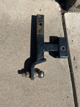 A black tow hitch ball mount with a chrome ball, an essential accessory for RV rental towing, on concrete.