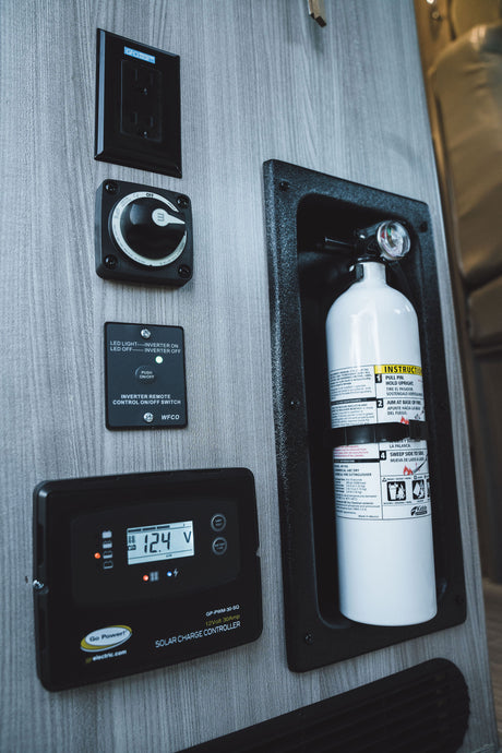 RV rental interior: solar charge controller, inverter switch, GFCI outlet, and fire extinguisher for essential controls.