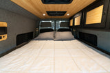 RV rental: Cozy camper van bed with wood ceiling, grey walls, integrated storage, and reading light for comfort.