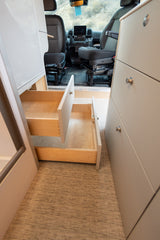 View inside an RV rental showing custom cabinetry with open drawers and the front cabin, highlighting efficient storage solutions.