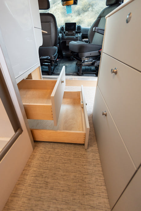 View inside an RV rental showing custom cabinetry with open drawers and the front cabin, highlighting efficient storage solutions.
