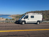 White camper van on a road overlooking a desert lake. Perfect RV rental for scenic adventures!