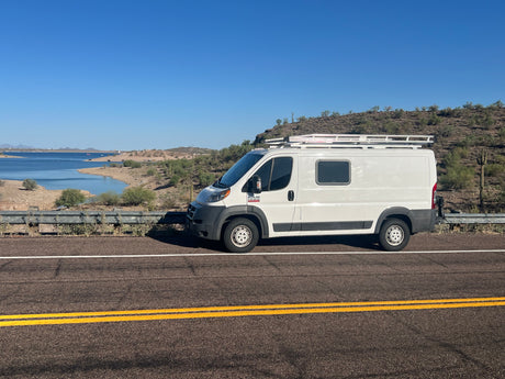 White camper van on a road overlooking a desert lake. Perfect RV rental for scenic adventures!