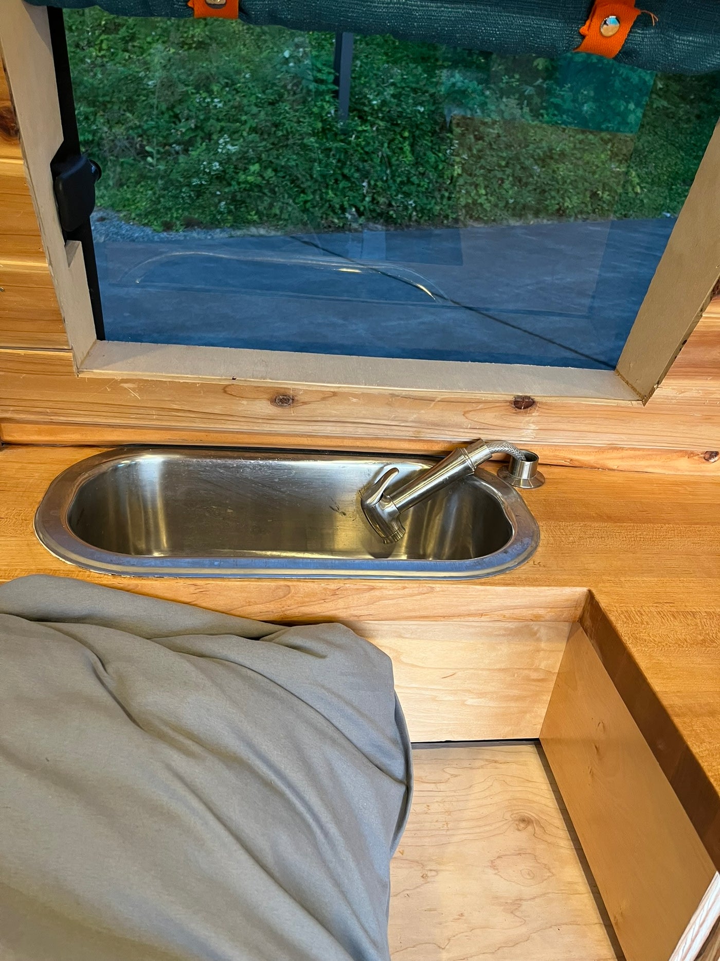 RV rental interior: A compact stainless sink & wooden counter with a window view to nature. — photo 16