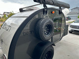 This Bean teardrop camper, a compact RV rental, features an awning and spare tire for your next adventure.