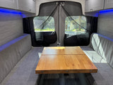 Cozy RV rental interior with a modular dinette, wrap-around seating, blue LEDs, and mesh back doors for comfort and ventilation.