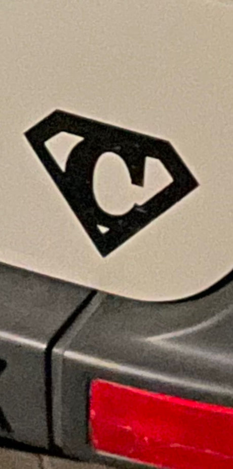 A unique, Superman-style 'C' logo on an RV rental vehicle, visible on its light-colored body above a red reflector.