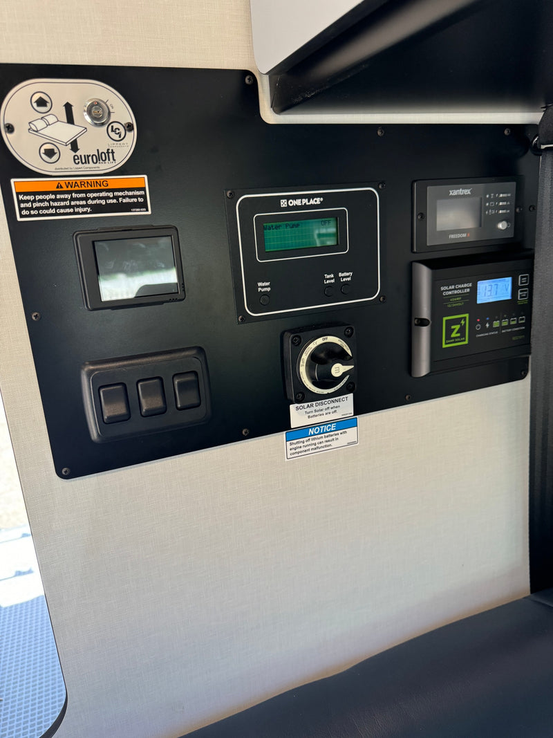 This RV rental control panel shows monitors for bed lift, water, power, and solar charge, with system management switches. — photo 15